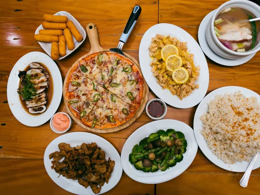 A spread of Island Wok dishes — pizza, lemon chicken, squid, vegetables and rice