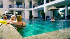 A couple of individuals enjoying leisure time together in a swimming pool under a clear blue sky.